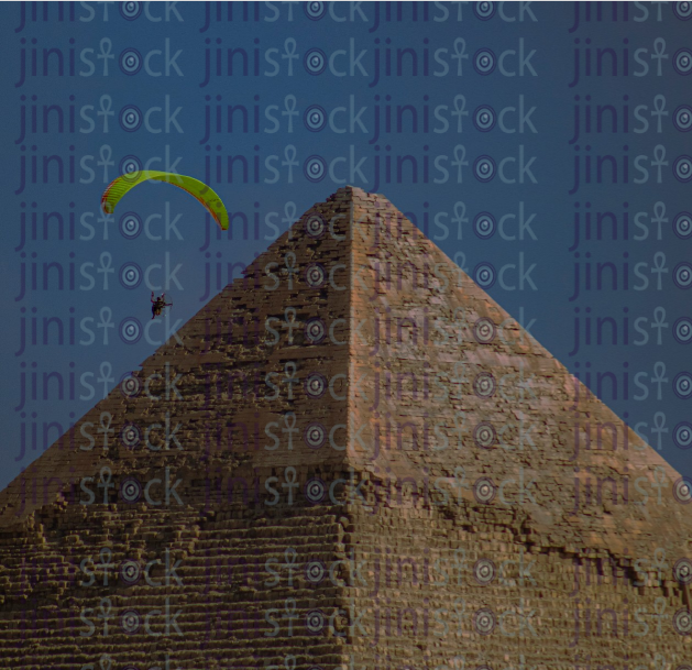 A man flies with a parachute over the pyramid - stock image