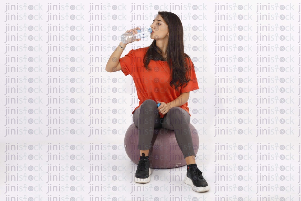 A female model is working out and drinking water on isolated background