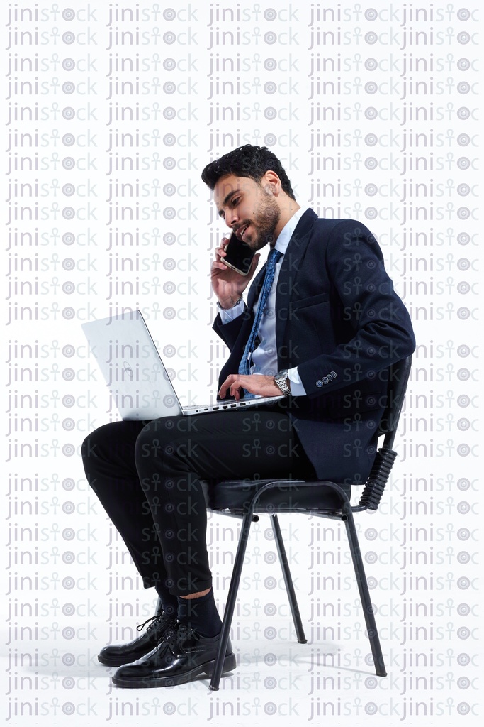 employee in a business suite working on a laptop and talking on the phone