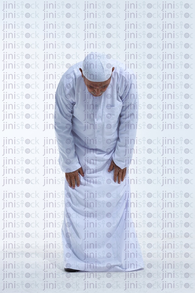 old man praying in a white galabia full length