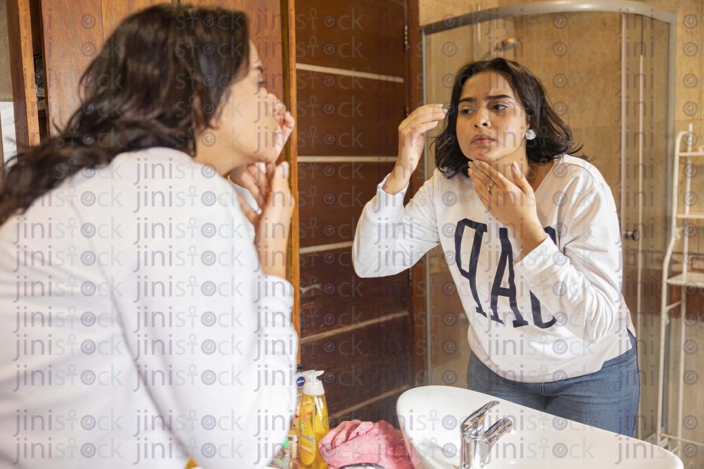 woman checking her face in the mirror for skin problem