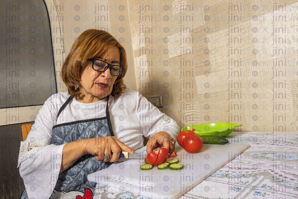 old woman cutting vegetables in the kitchen