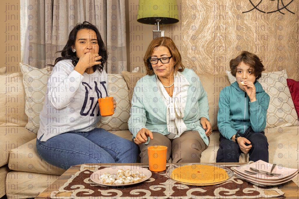 Family gathering watching TV and eating snacks