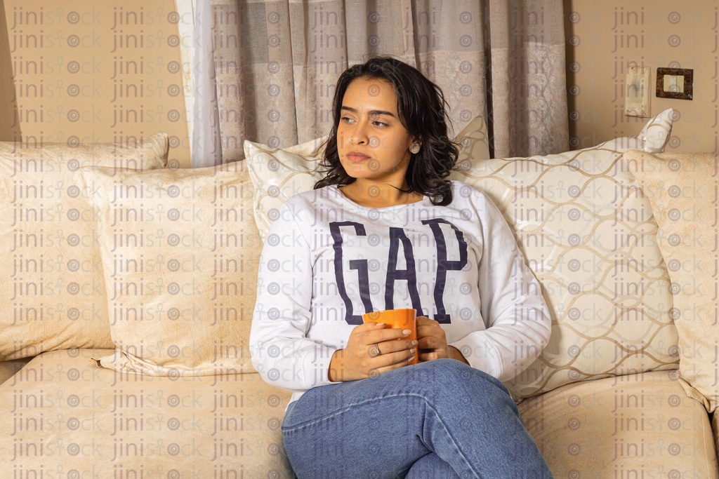 Woman enjoying her time drinking tea or coffee on the couch