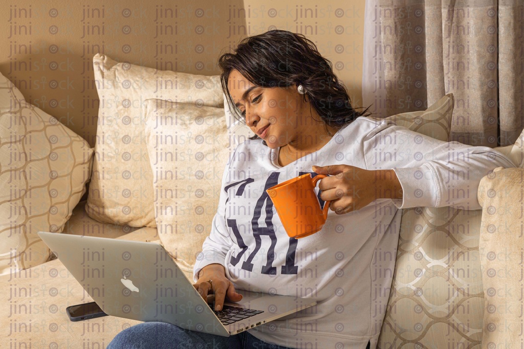 woman drinking tea while watching something on the laptop