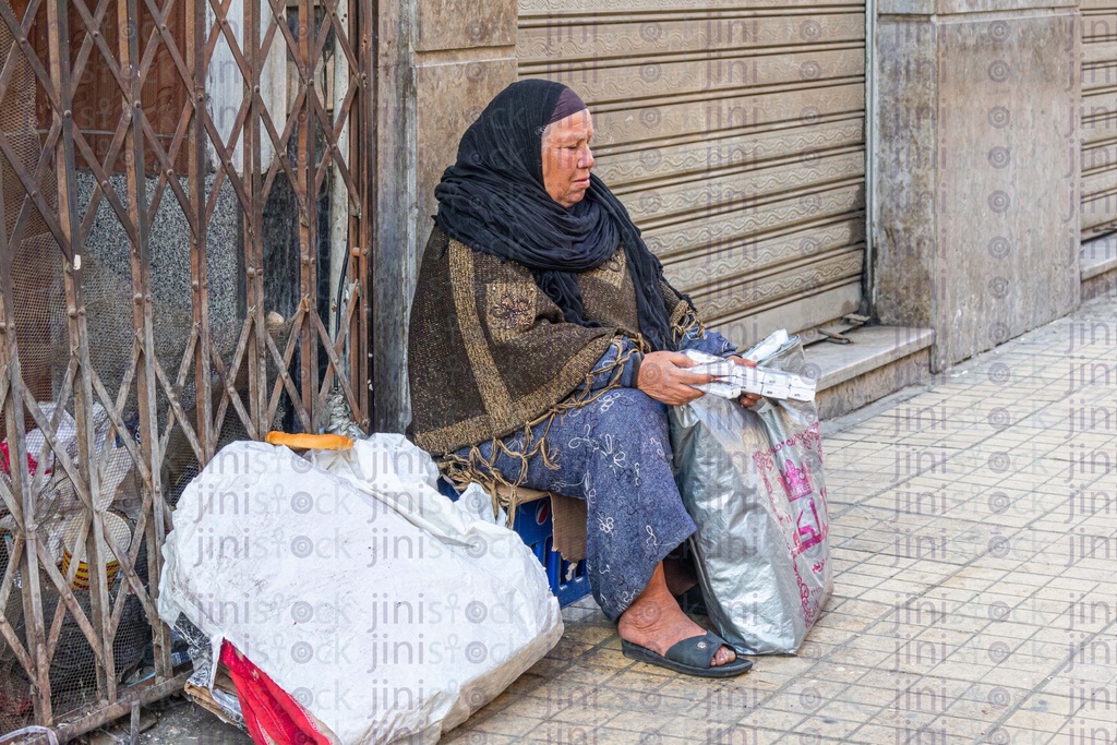 woman sitting begging on the side of the street