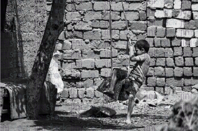 boy playing an a swing in rural area - stock image