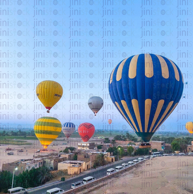 Air balloon in Luxor flying over a green field.