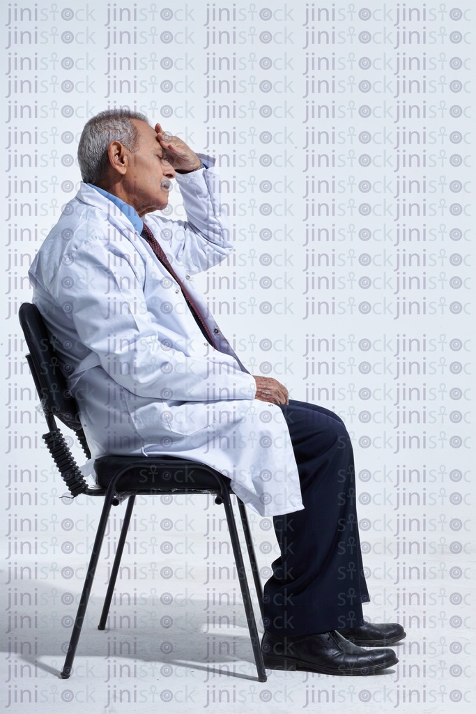 old doctor tired with a headache sitting down side view