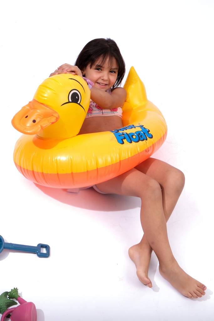 little girl swimming with duck water floater in a pool