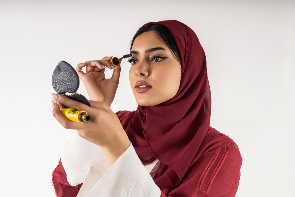 صورة عالية الجودة لامرأة خليجية ترتدي فستانًا أحمر وتضع مكياجها.