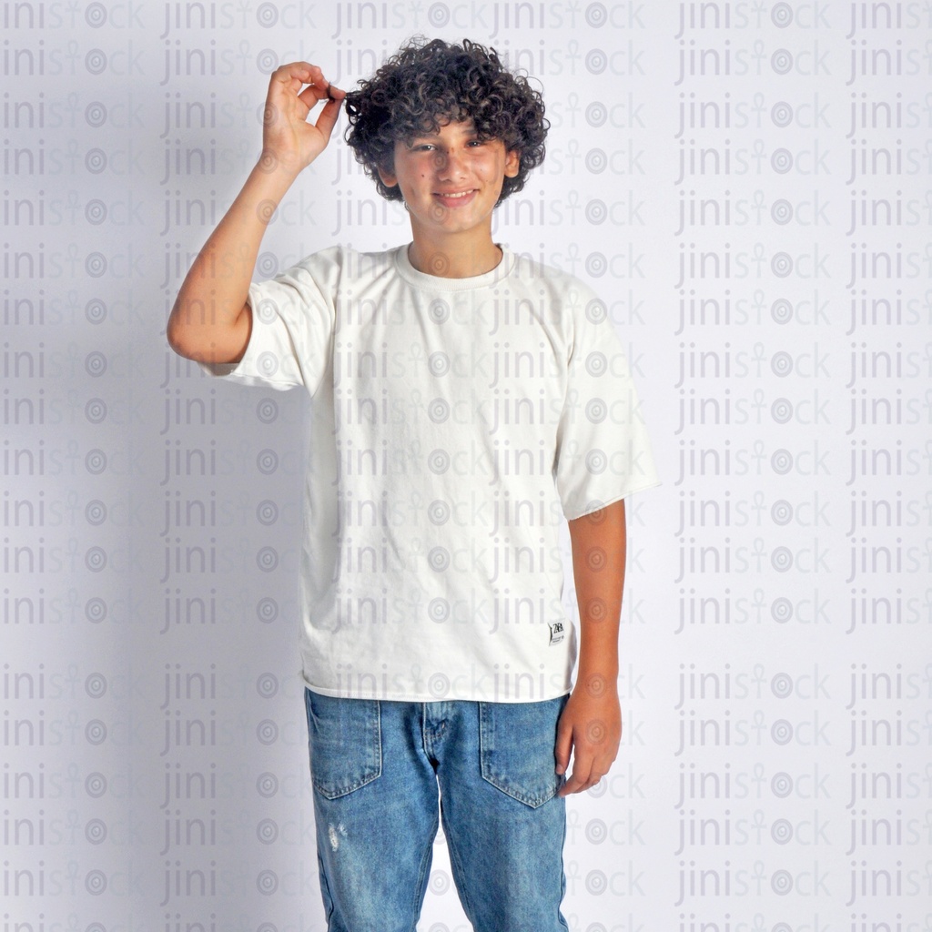 A teen boy playing with his curly hair