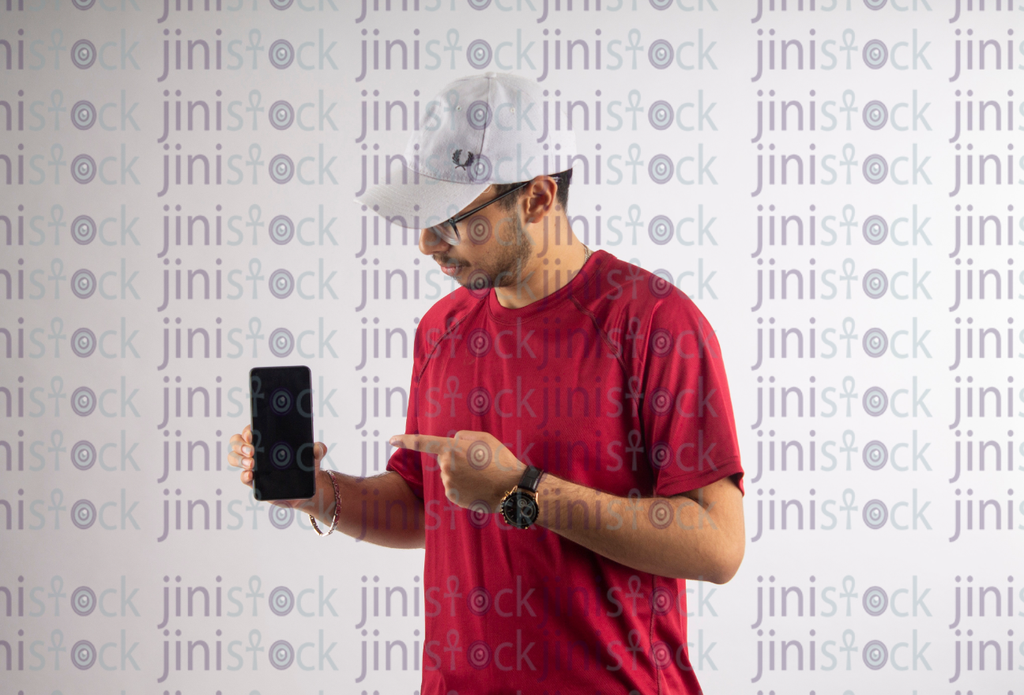 man with white hat and eye glass pointing at a mobile- stock image