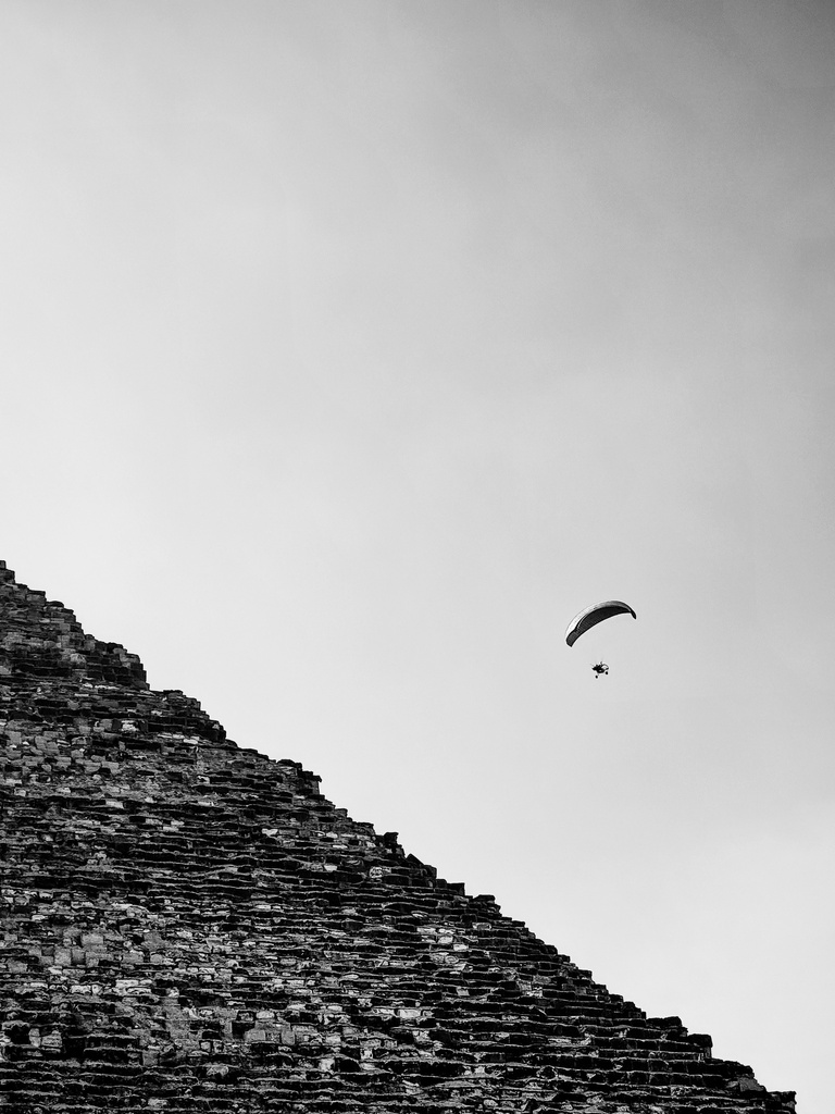 Parachute flying over the pyramids in black and white