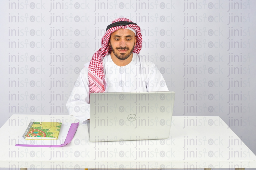 رجل سعودي أو خليجي يعمل على جهاز كمبيوتر محمول في المكتب