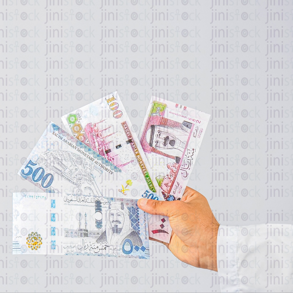 Close-up shot of a hand of a Saudi man holding Saudi riyals