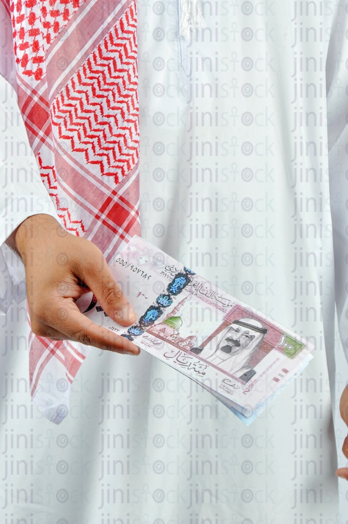 Close-up shot of a Saudi man 's hand holding Saudi riyals