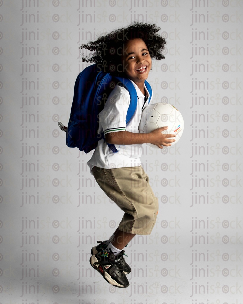 A happy child going to school holding a ball