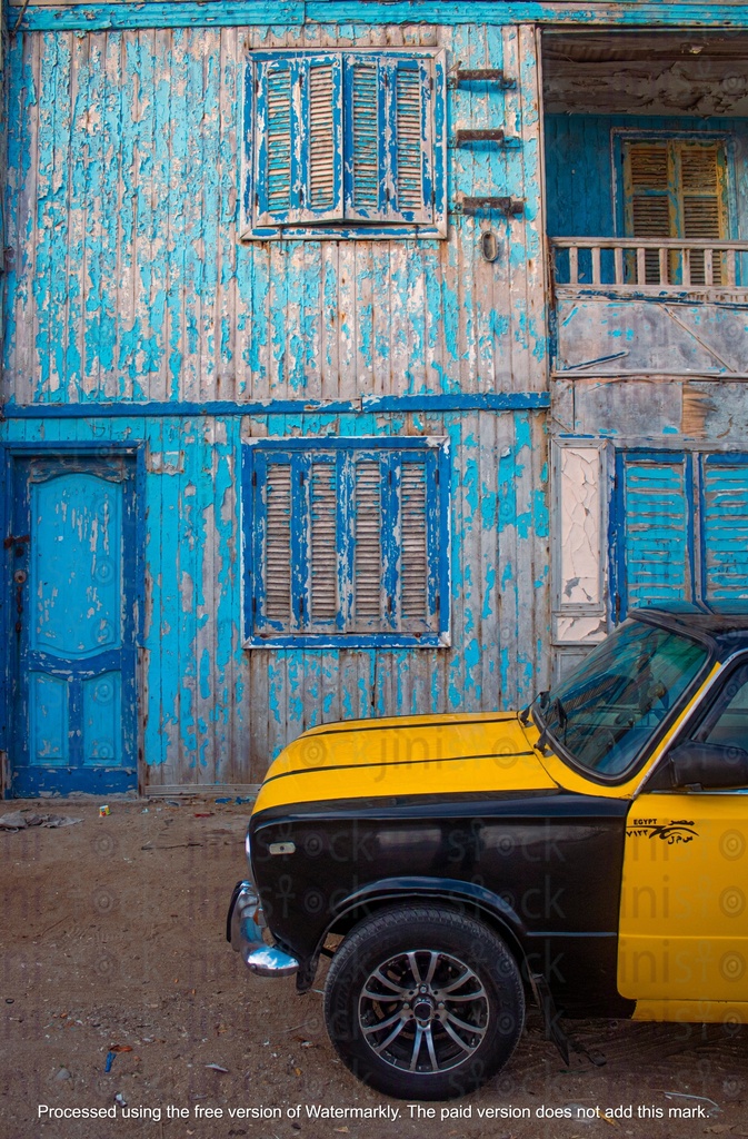 black and yellow taxi parked in front of a wooden hut