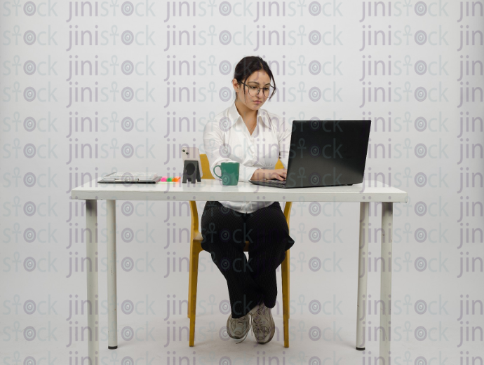 Woman sitting at desk - working on laptop - cup of coffee in front of her - close front shot - stock image