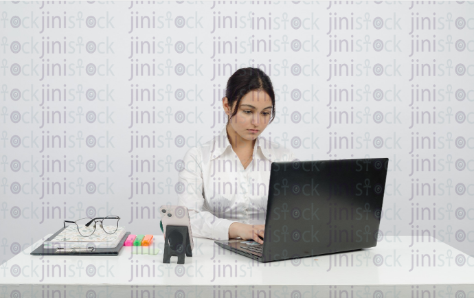 Woman sitting at desk - working on laptop - front close-up - stock image