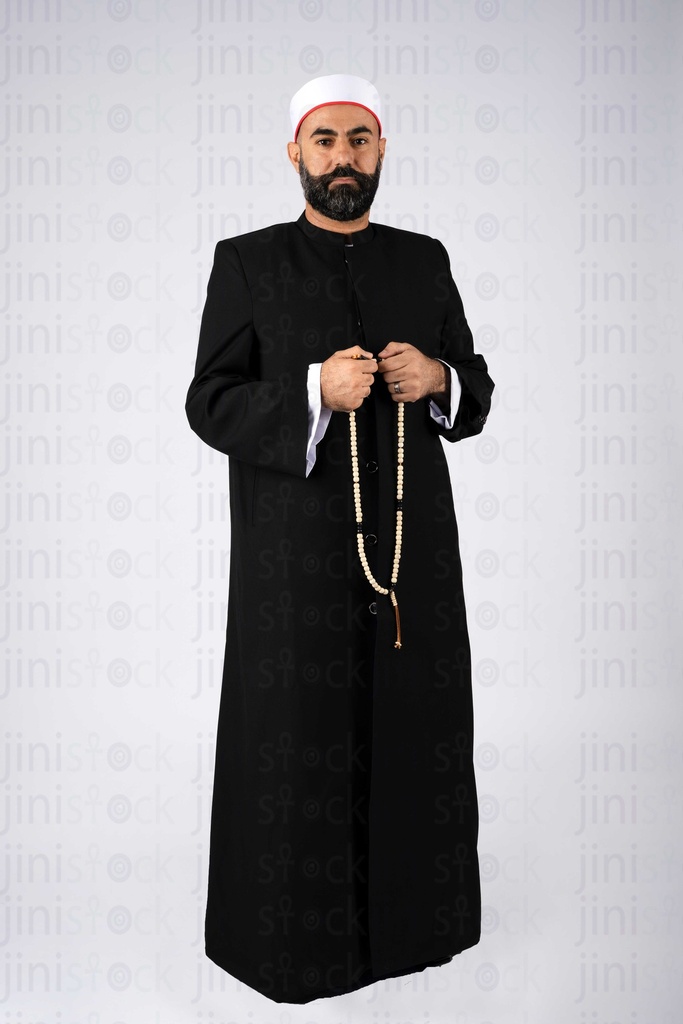 A sheikh is standing holding a rosary