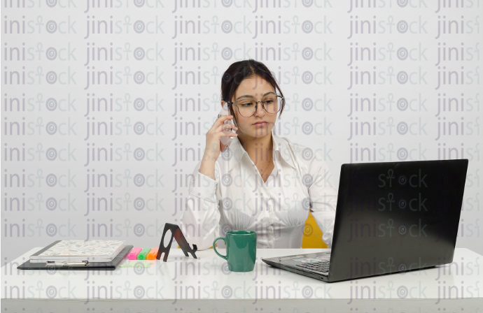 Woman sitting at desk - working on laptop - wearing glasses - frontal close-up - stock image