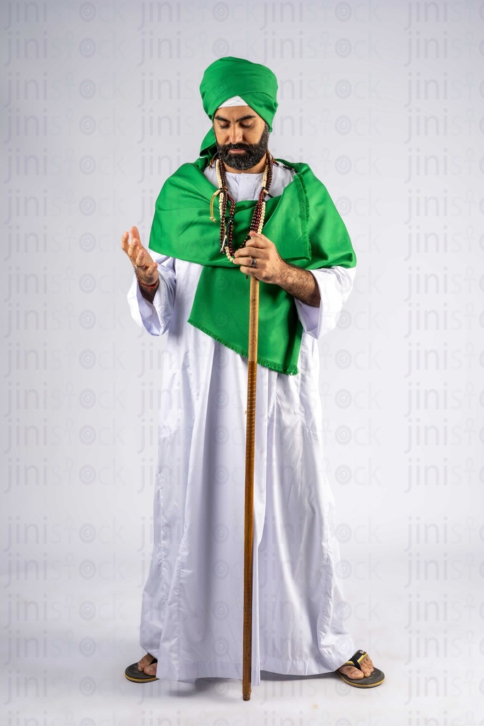 A man in a green turban and holding a stick