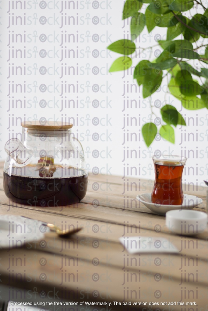 tea cup and tea pot on a table next to a green leaves