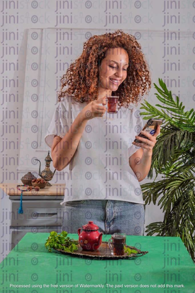 girl holding her tea cup while looking at the mobile