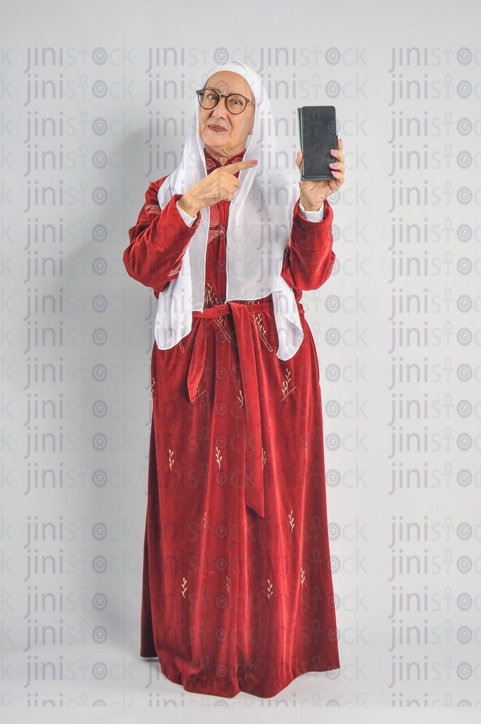 An Egyptian woman recommending a mobile app and pointing at the mobile phone in her hand.