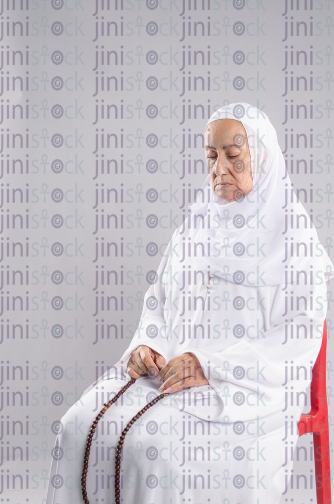 Old woman praying on a chair