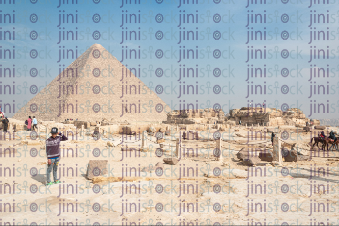 A child stands in front of one of the pyramids of Giza - stock image