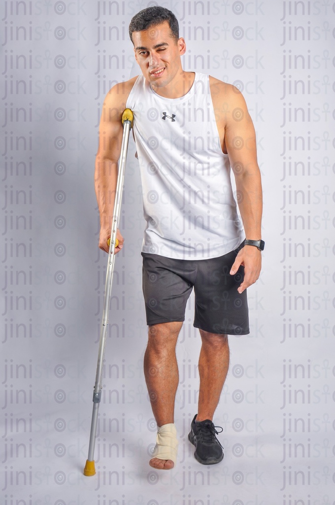 An athlete man has a foot injury and walking with a crutch