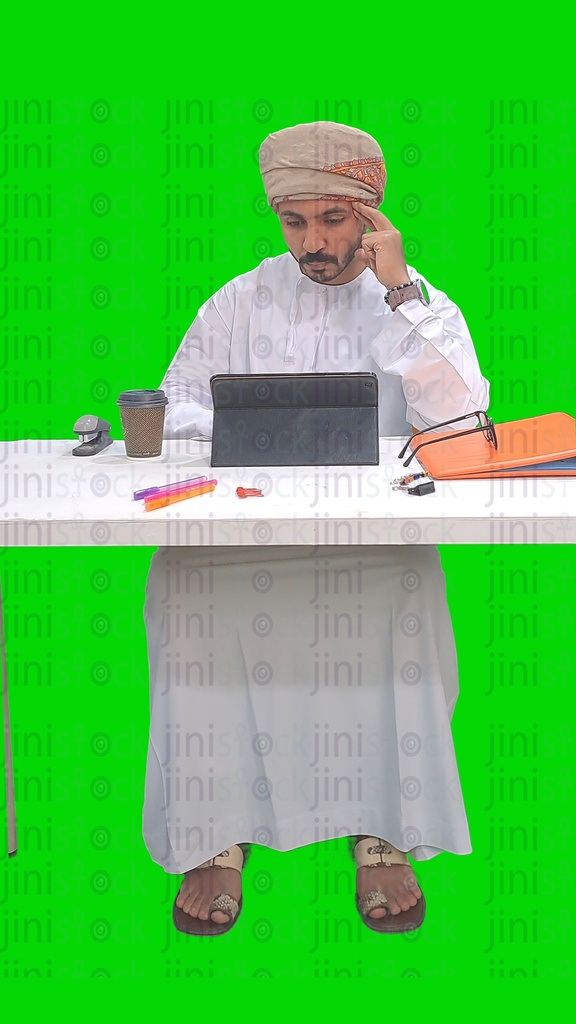 Omani man from the Gulf working on a tablet in his office and thinking about something