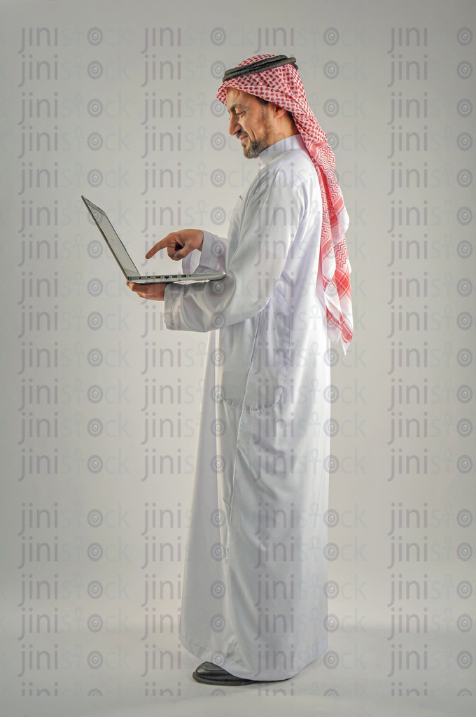 Khaliji, Saudi, Emirati, a man from the Gulf holding a laptop and working on it "side view"