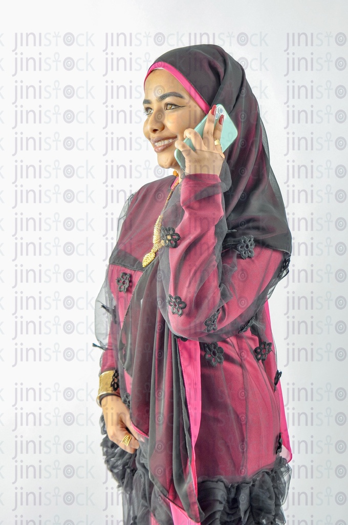 A Nubian Egyptian woman wearing Nubian clothes, putting a veil on her hair, and talking on the mobile phone
