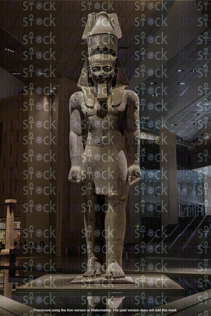 An Egyptian girl stands in front of the statue of Ramses II inside an Egyptian museum.