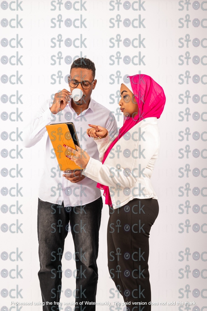 A veiled Nubian girl holding an orange file stands next to a Nubian young man drinking coffee