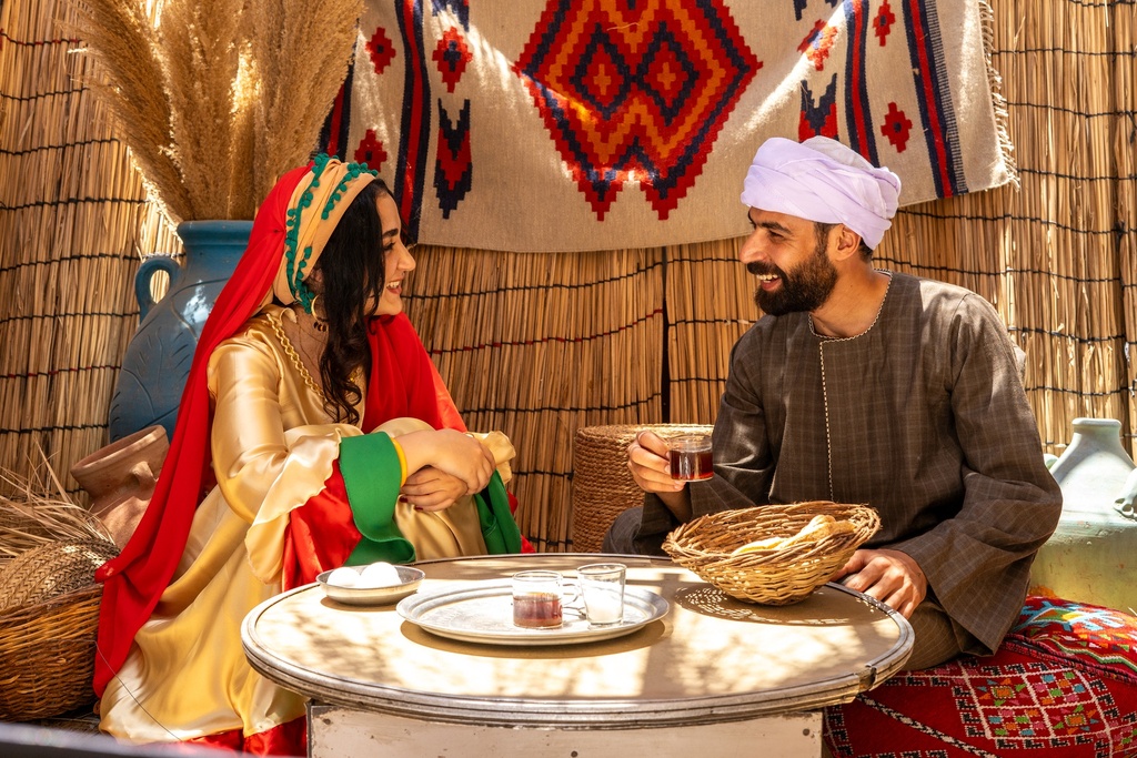 Egyptian man sitting on a tray with a girl in a beautiful peasant costume 