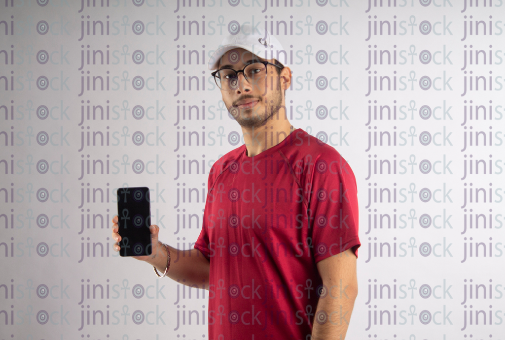 man with white hat and eye glass holding a mobile- stock image