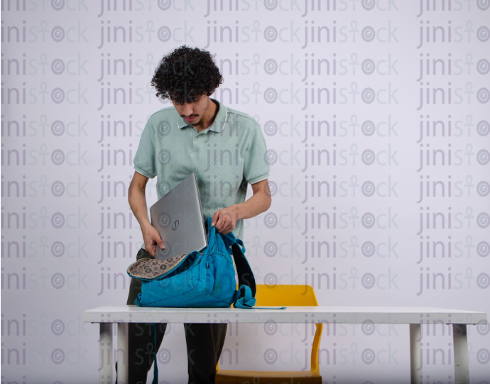 young man student packing his laptop in his backbag - stock image