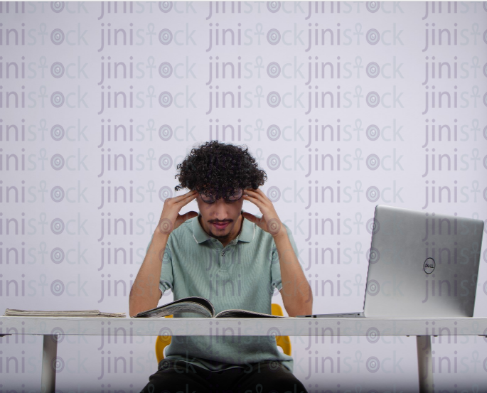 young man with a headache while studing - stock image