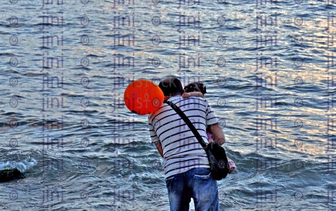 a stock image with high quality of a man on the sea holding a kid with a balloon