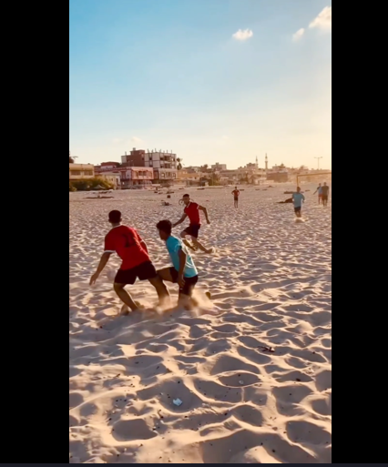 boys playing football on a beach