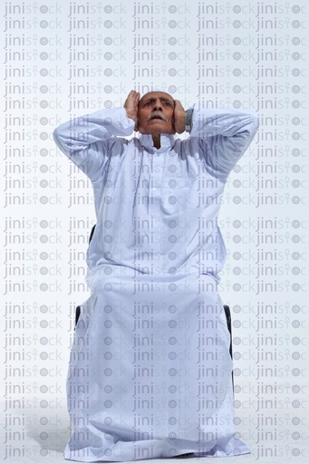 old man praying on a chair in a white galabia