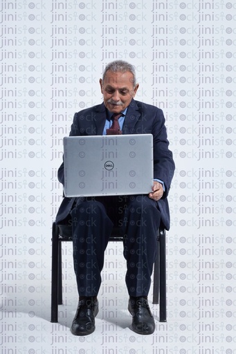 old man in a suite on a laptop