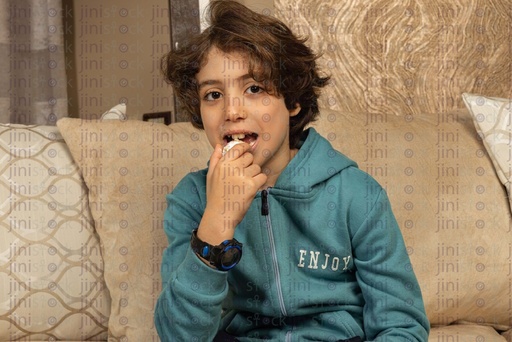 boy taking a bite of biscuits or Al eid kahk