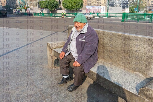 Depressed man looking at the floor while sitting on a bench