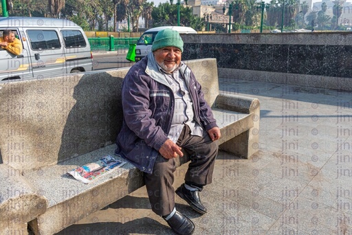 old sad man sitting on a bench on a street